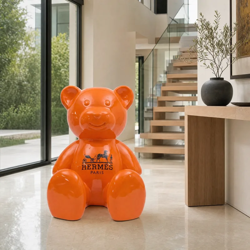 Orangefarbene sitzende Teddybär-Skulptur in einem hellen Eingangsbereich