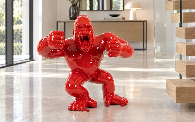 Rote Gorilla-Skulptur in Hochglanz im hellen Eingangsbereich eines modernen Hauses mit Holztreppe
