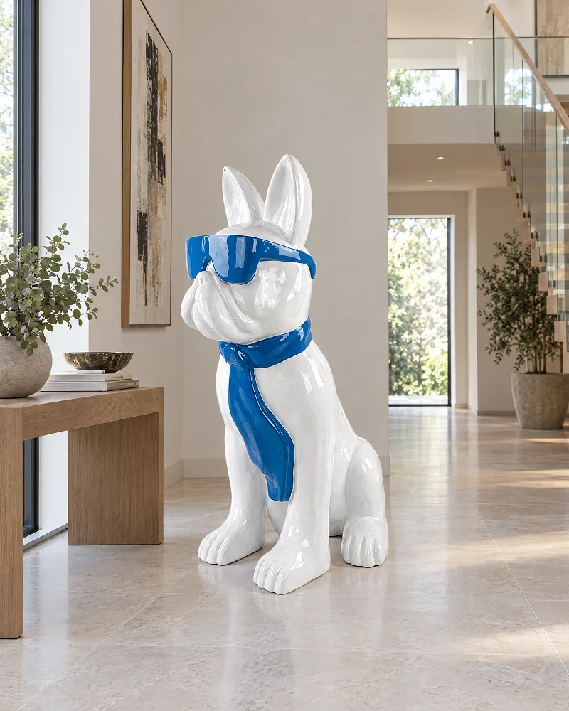 Sitzende weiße Bulldogge mit blauer Sonnenbrille und blauem Tuch im Flur neben einer Holzkonsole