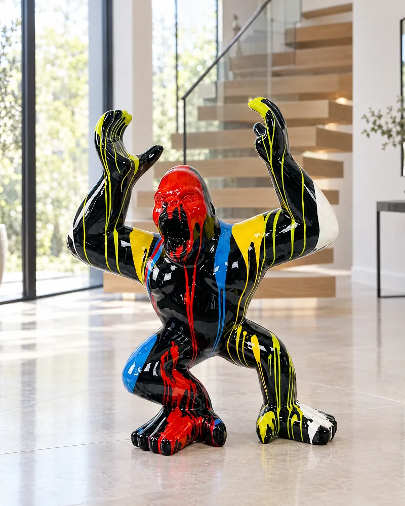 Schwarze Gorilla-Skulptur mit erhobenen Armen und bunten Farbläufen in einem hellen Wohnraum